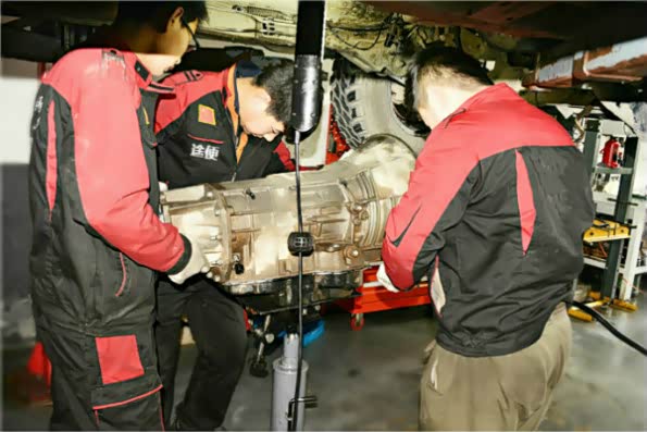 抬下分动箱后，几位维修技师配合着抬下吉普大指挥官变速箱，要注意周围配件