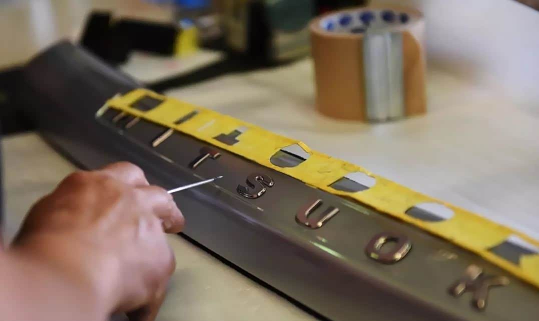 工人手工制作车身上的品牌LOGO