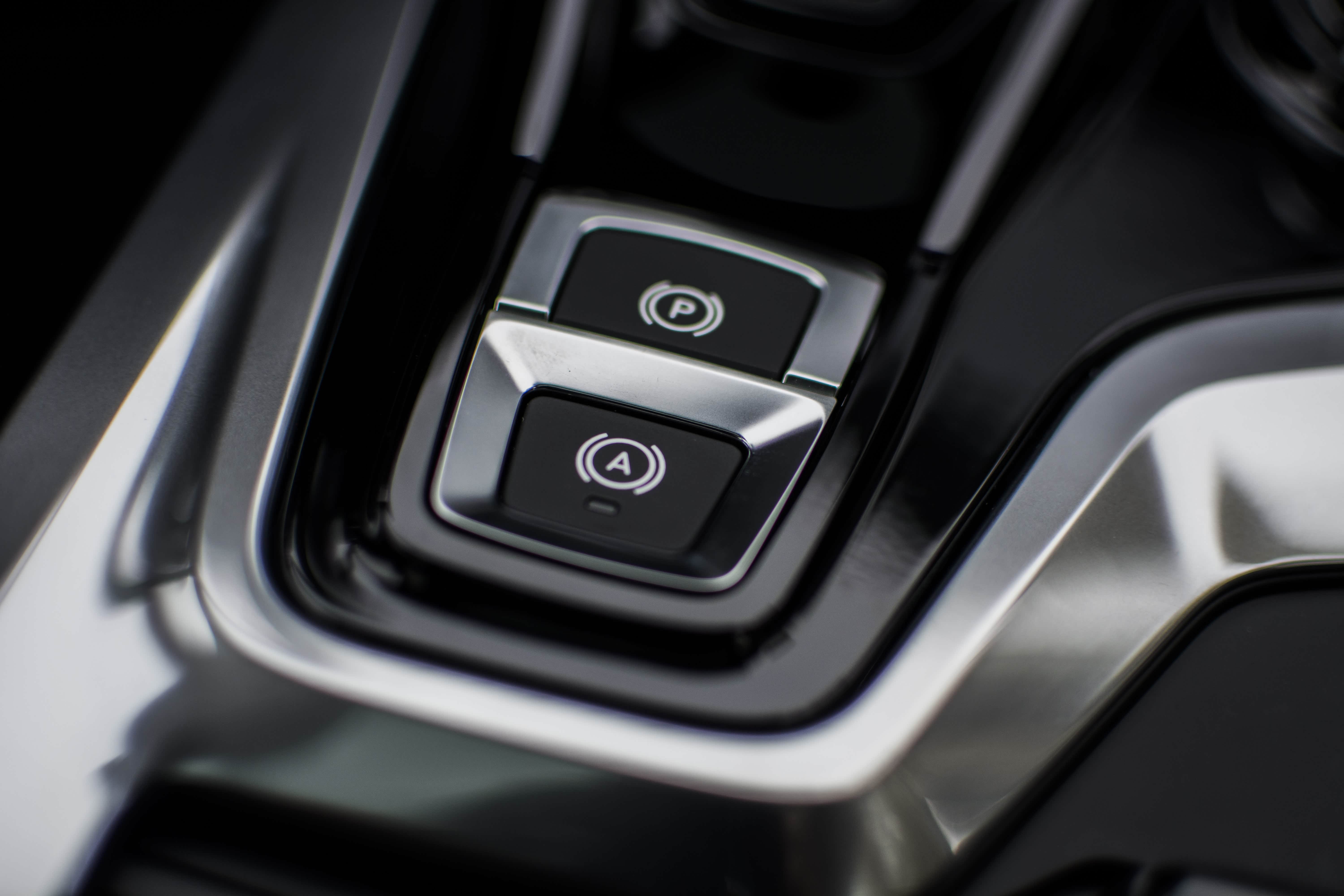 踩住刹车上下拉按来开启或关闭电子驻车，后面带A的按钮是自动驻车。